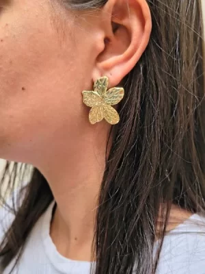 Brinco flor com 5 pétalas banhado a ouro 18k, na orelha de uma modelo.