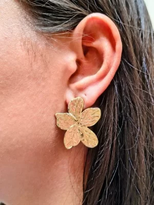 Brinco flor com 5 pétalas banhado a ouro 18k, na orelha de uma modelo.