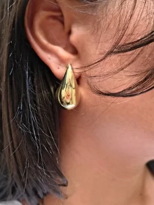 Brinco Gota G Banhado a Ouro 18k, na orelha de uma modelo.